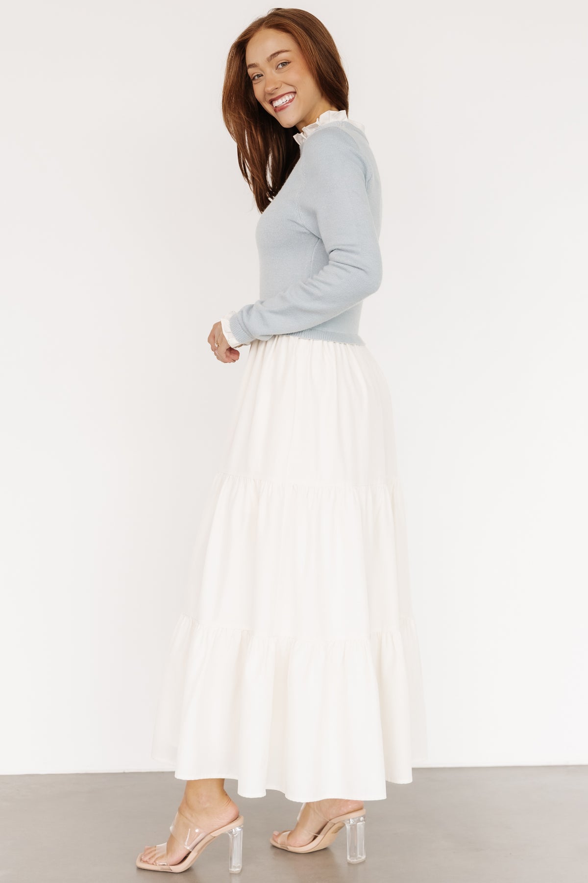 Close-up of the ruffled neckline and textured sweater-knit bodice in the light blue Sophie Sweater Dress showing cuff ruffle detail.
