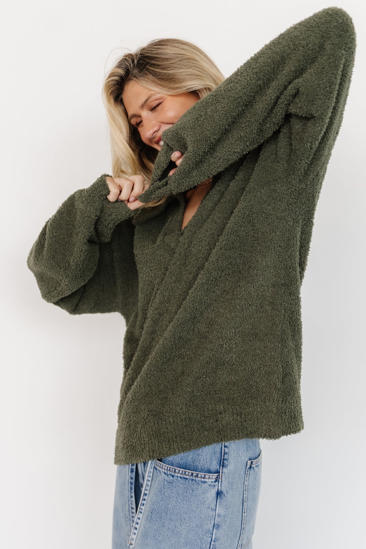 Flat-lay of Lockwood sweater in muted green folded to display collar, ribbed hem and fabric composition label.