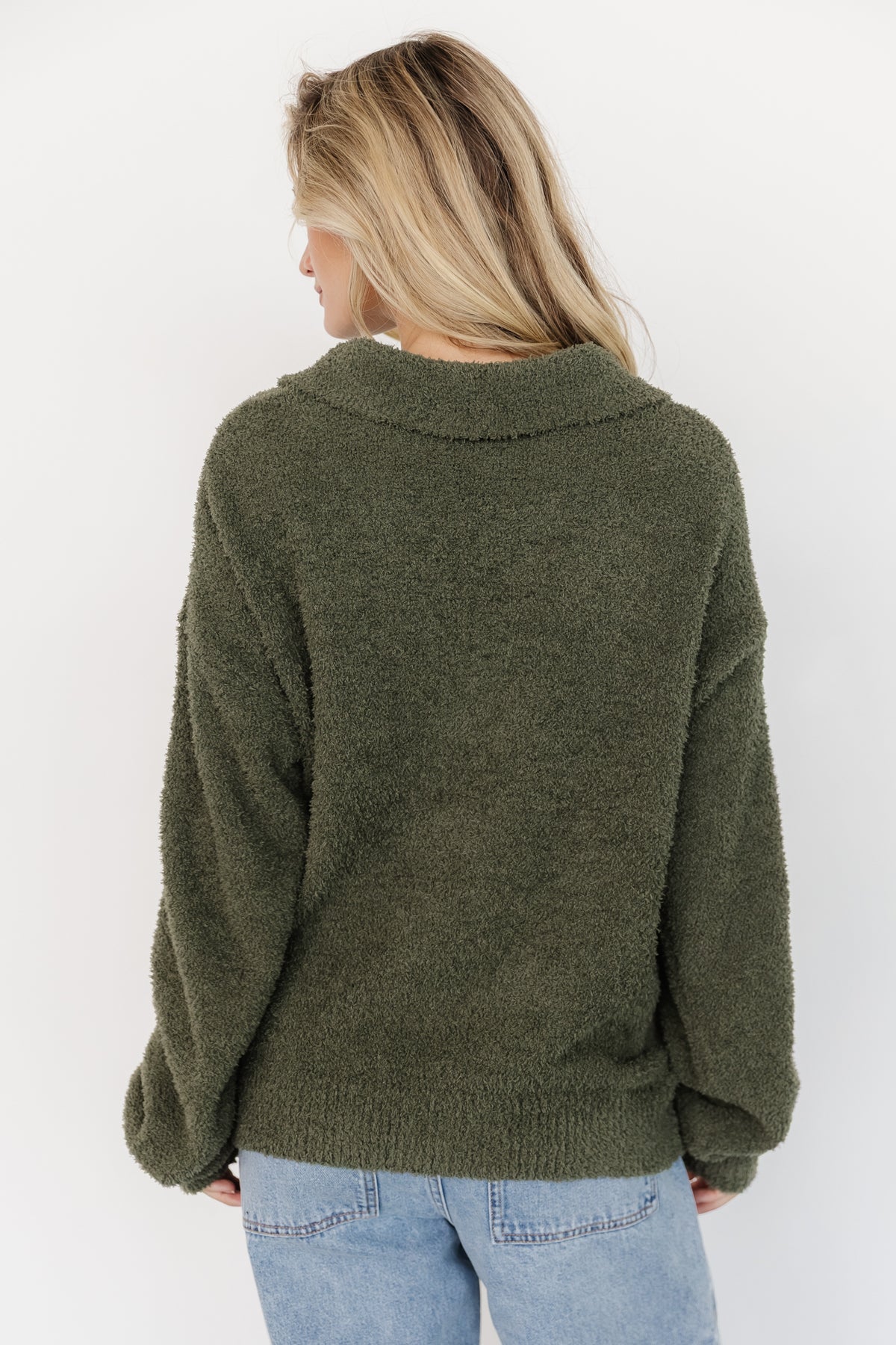 Styled outfit showing Lockwood sweater paired with light-wash wide-leg jeans for a casual layered look in muted green.