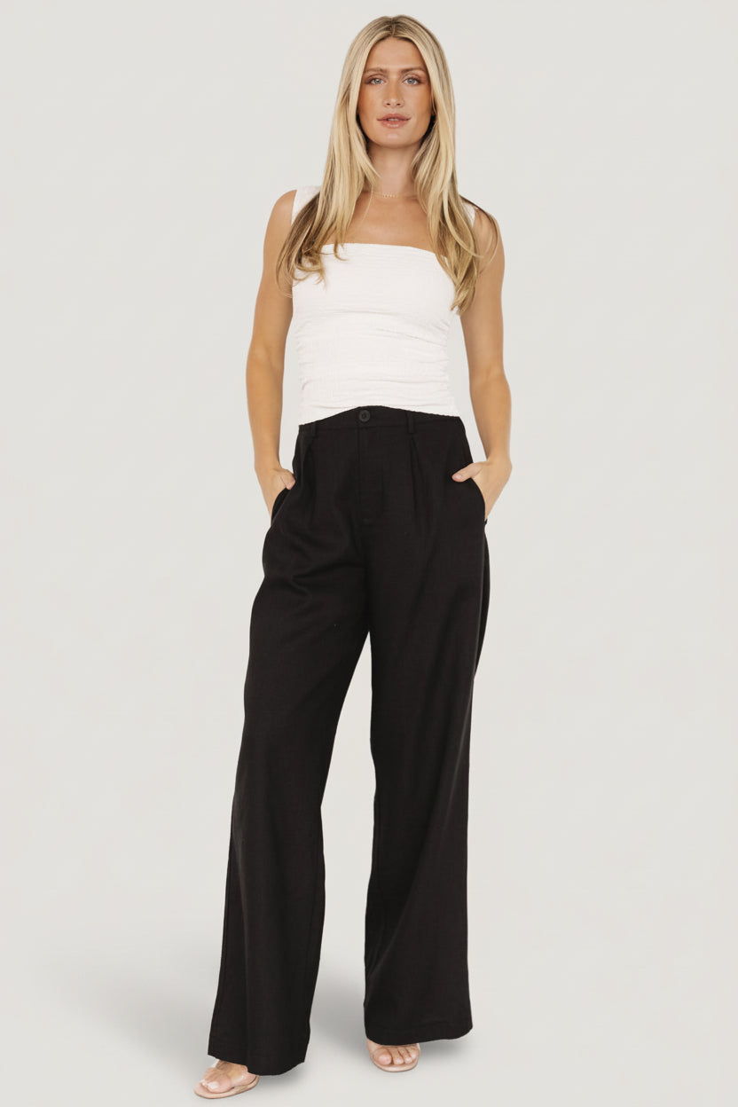 Side profile of Malin wide leg pants in black on model, highlighting functional side pockets, smooth lining, and a relaxed wide silhouette.