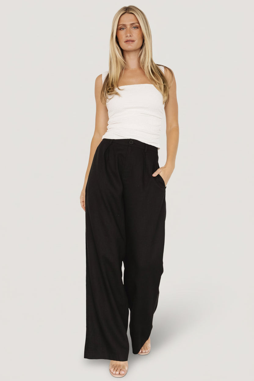 Detail image of Malin pants showing belt loops, button-and-zip closure, and a crisp front crease for a polished look.