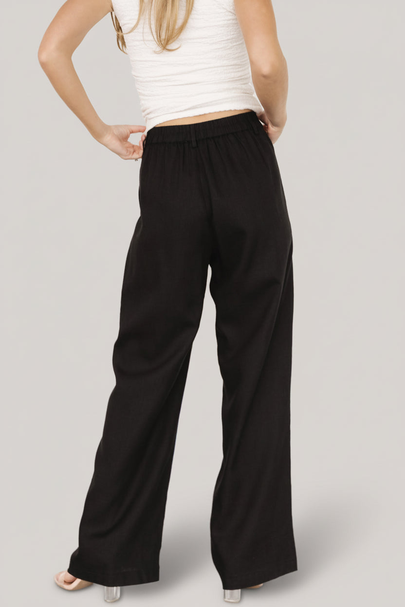 Full-length studio image of Malin trousers in black, demonstrating the trouser-style front crease and smooth fully lined interior drape.