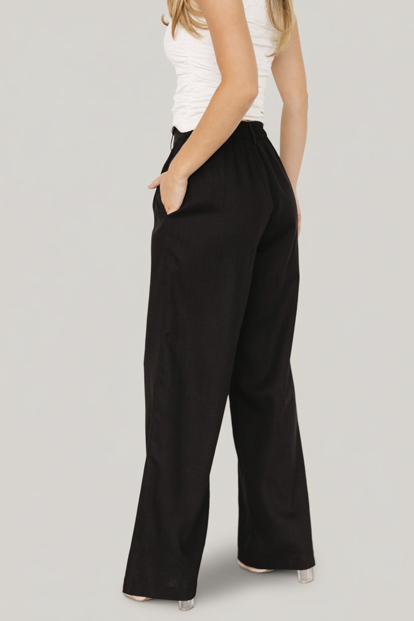 Close-up of Malin pants fabric and waistband in black, showing the 70% viscose 30% linen texture and back smocked elastic detail.