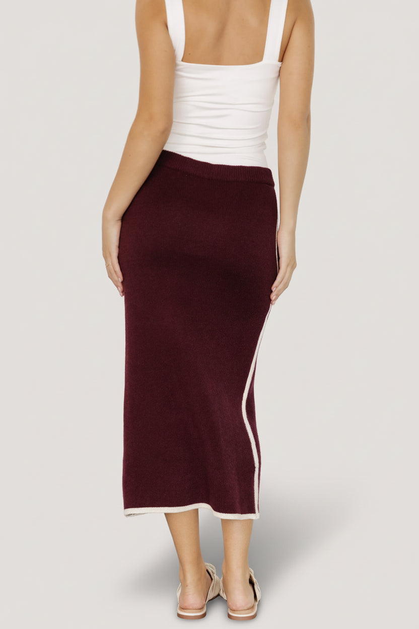 Close-up detail of the Ava Knit Midi Skirt in wine highlighting the soft knit fabric, cream piping, and fine stitch texture.