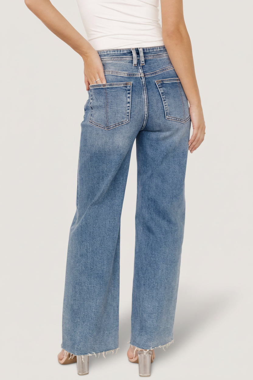 Model seated wearing Noah high-rise jeans in medium wash, showing natural drape, straight leg, and casual lived-in finish.