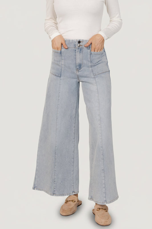 Front view of Emmi mid-rise wide-leg jeans in light wash worn by model, showing full-length flare and visible front pockets for styling.
