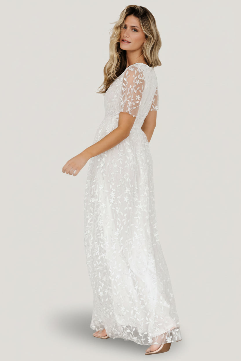 Styled flat-lay of Marseille vine-embossed organza maxi dress in white, emphasizing the raw cut hemline, sleeve shape, and embossed vine motif.
