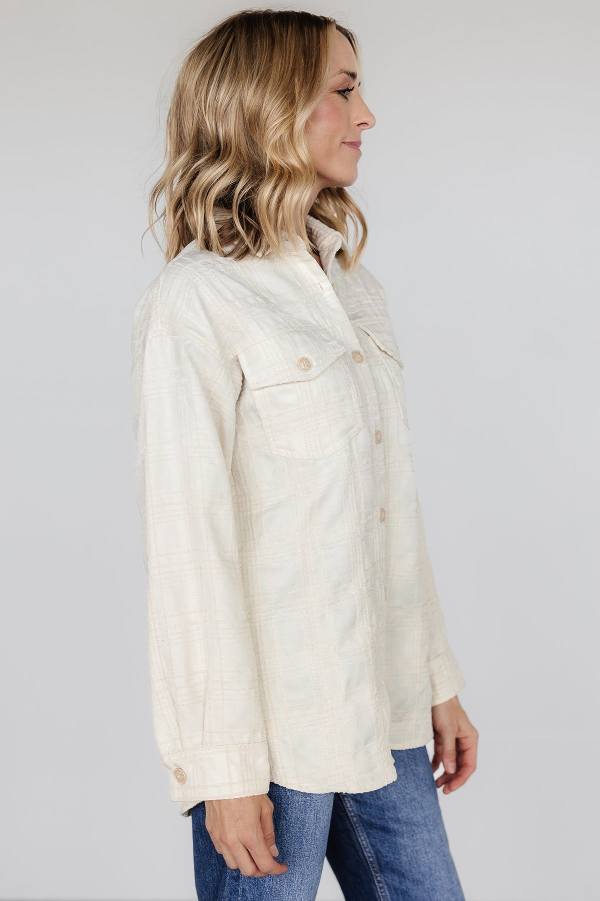 Side-angle view of Joanna Plaid Shacket in cream and natural, highlighting dropped shoulder, long sleeve with buttoned cuff, and textured plaid.
