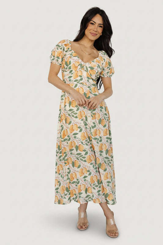 Front view of Amalfi lemon-print midi dress showing V-neck, ascending point paneling, smocked back, short elastic sleeves, and knee-length lining.