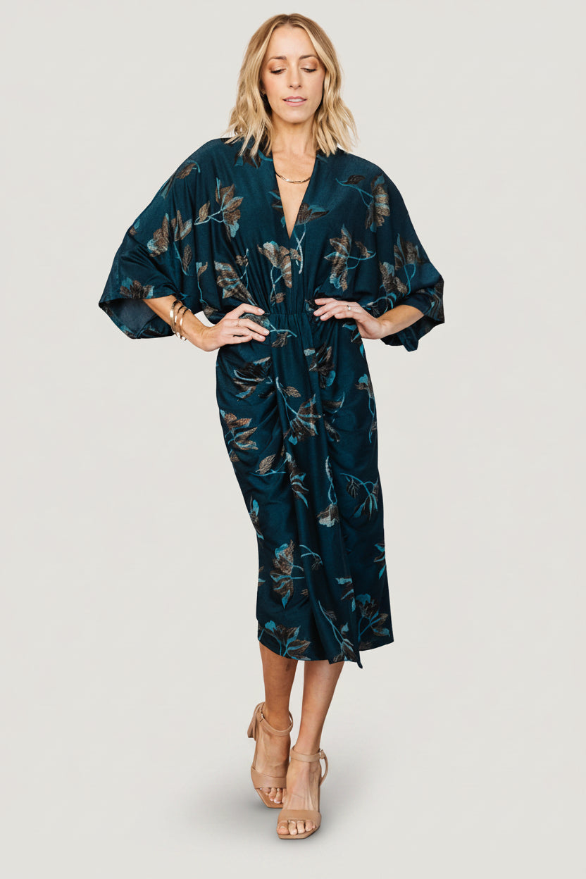 Front view of the Shaneen ruched midi dress in jade floral shimmer on model, showing deep V-neck, ruched waist and center slit.
