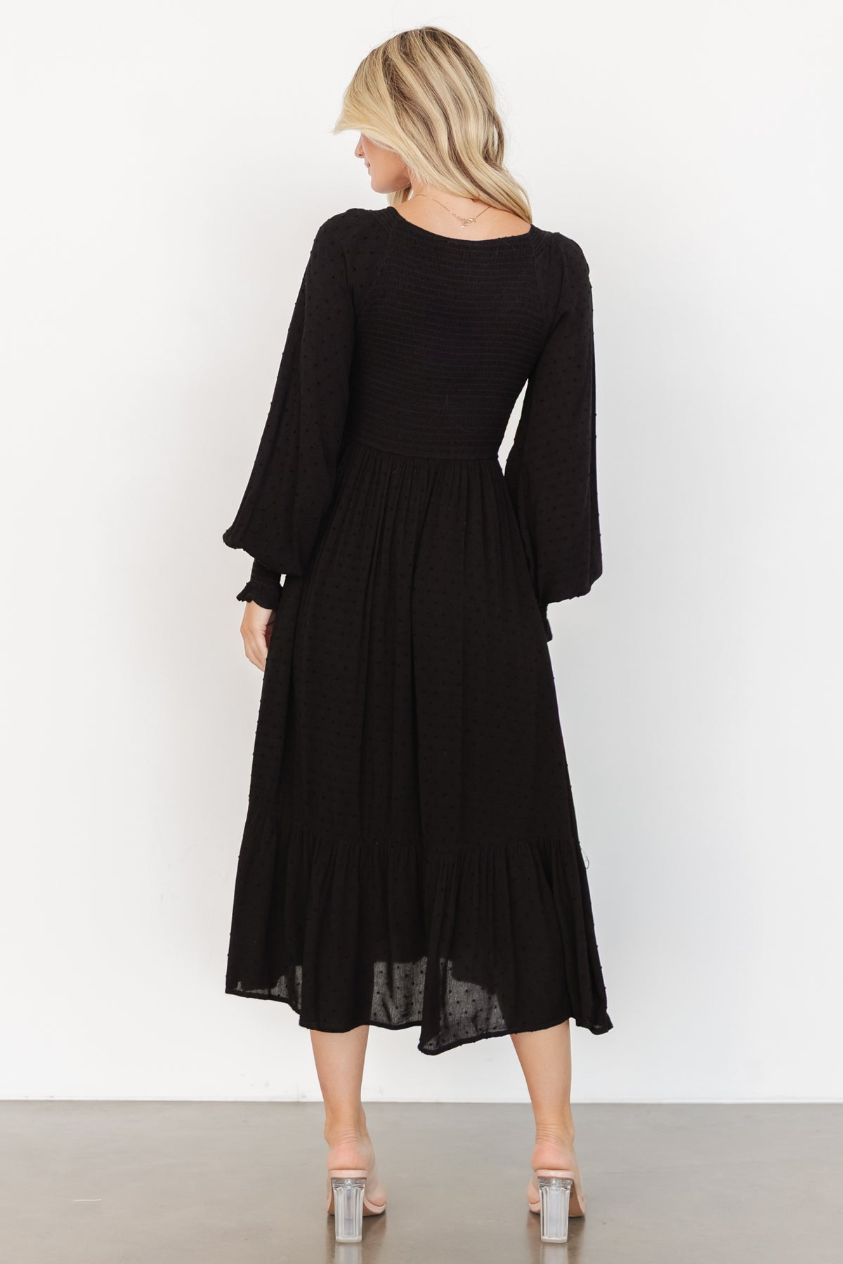 Close-up of smocked bodice and sleeve cuff on the black Lainey midi dress, displaying elastic smocking, dotted texture, and fabric drape details.
