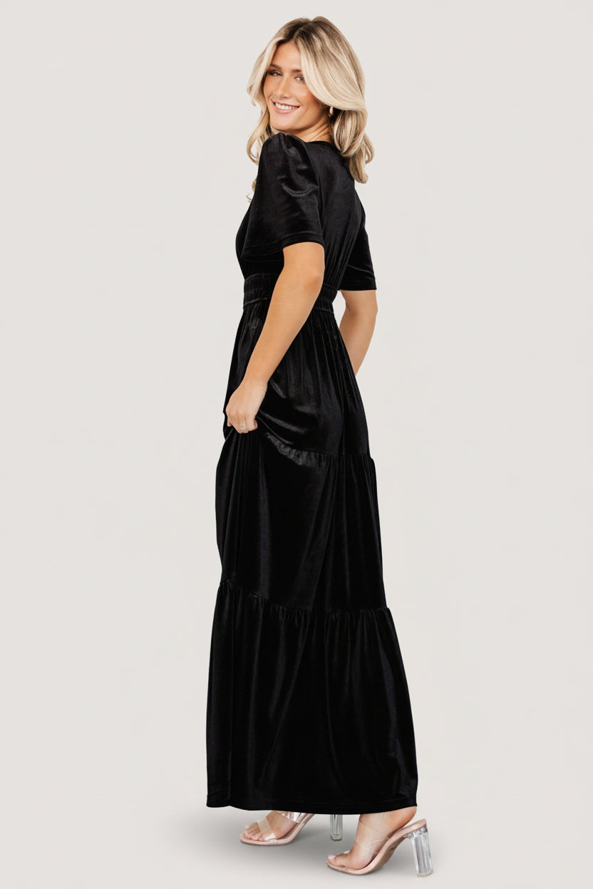 Back view of Artemis black velvet tiered maxi dress showing rear silhouette, tiered hem, and lightweight movement of fabric.