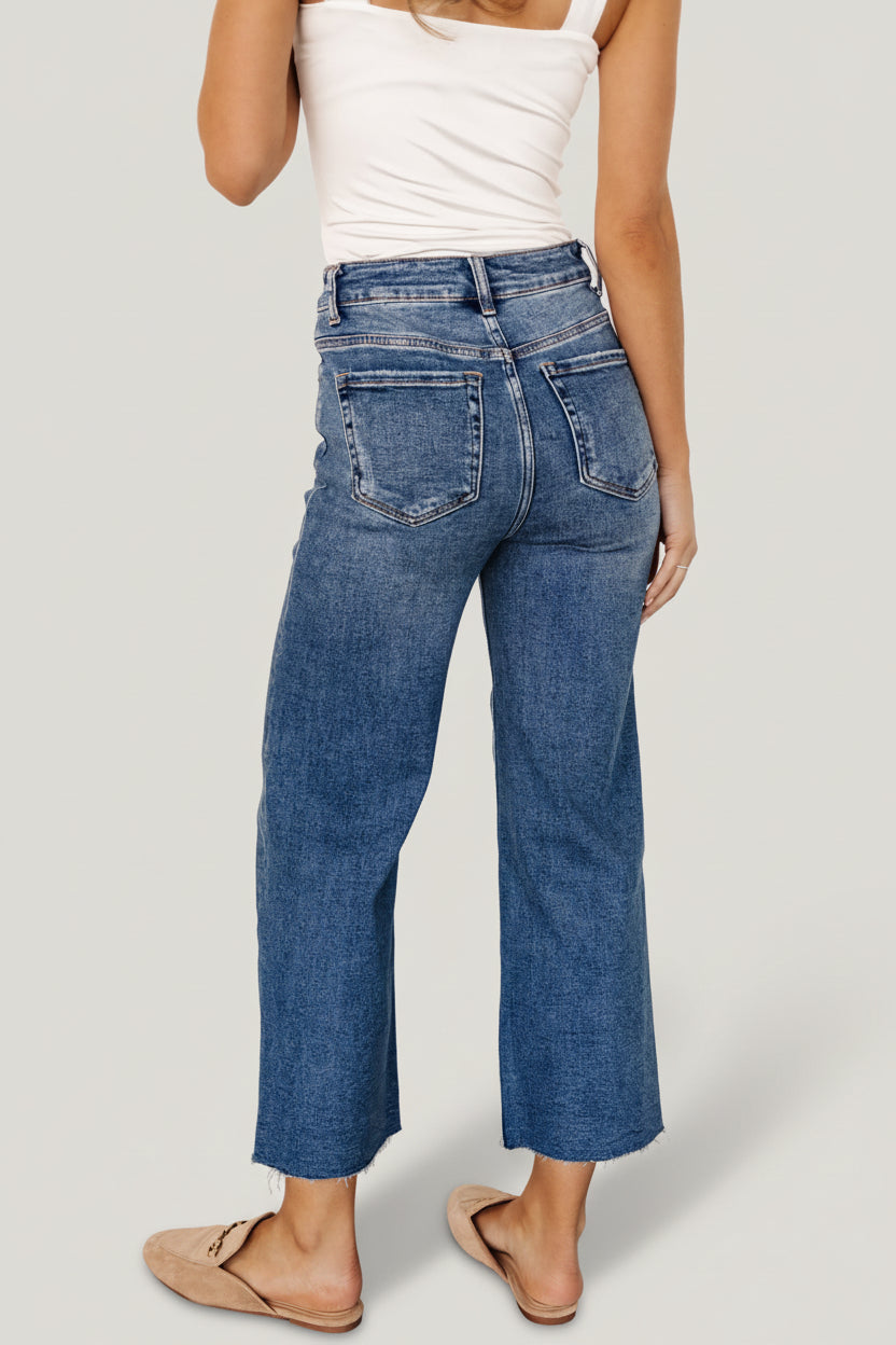 Close-up of medium wash denim fabric and distressed detail below the right front pocket on Kirby jeans.