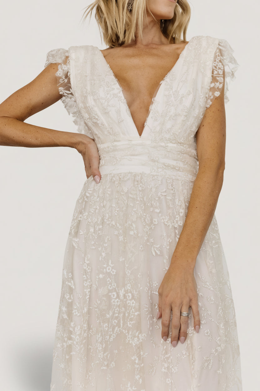 Three-quarter view of Arlene Shimmer Maxi Gown in ivory showing tulle frill sleeves, deep V-back, and a graceful leg slit.