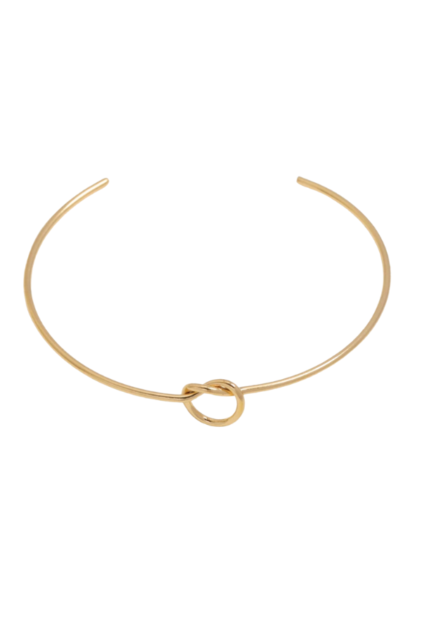 Flat lay of The Kate Bangle beside coordinating accessories, highlighting the warm gold knot and open cuff silhouette on a clean background.