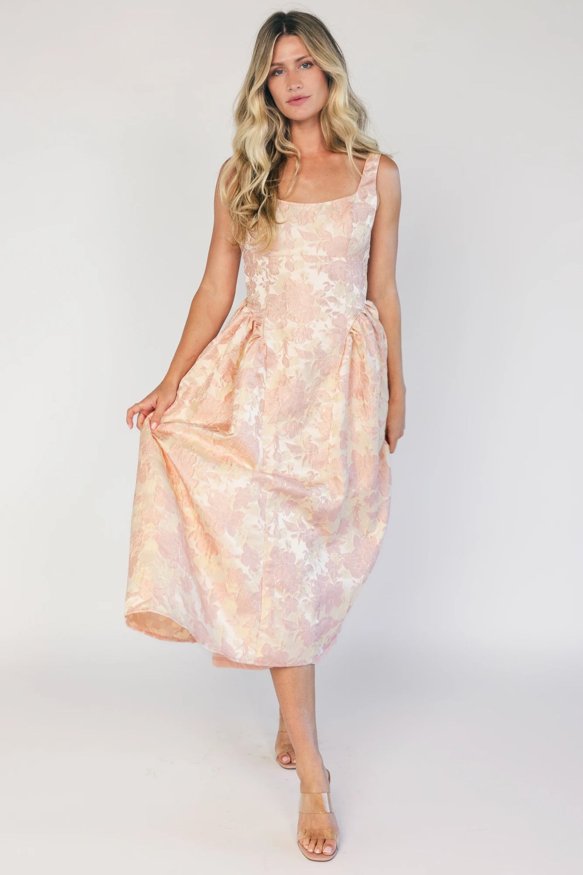 Model wearing a peach floral jacquard midi dress with a square neckline, wide tank straps, and a fitted bodice.