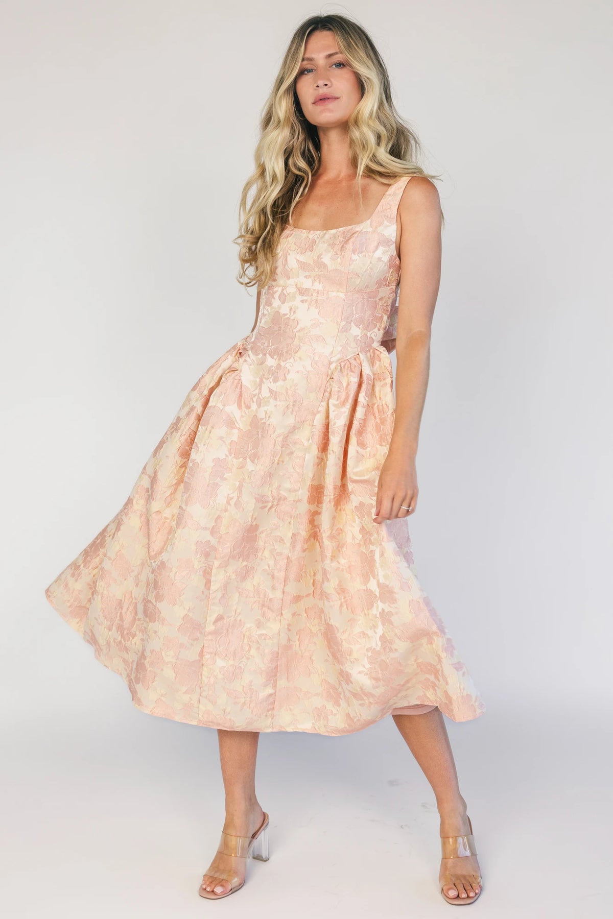 Model wearing a peach floral jacquard midi dress with a square neckline, wide tank straps, and a fitted bodice.
