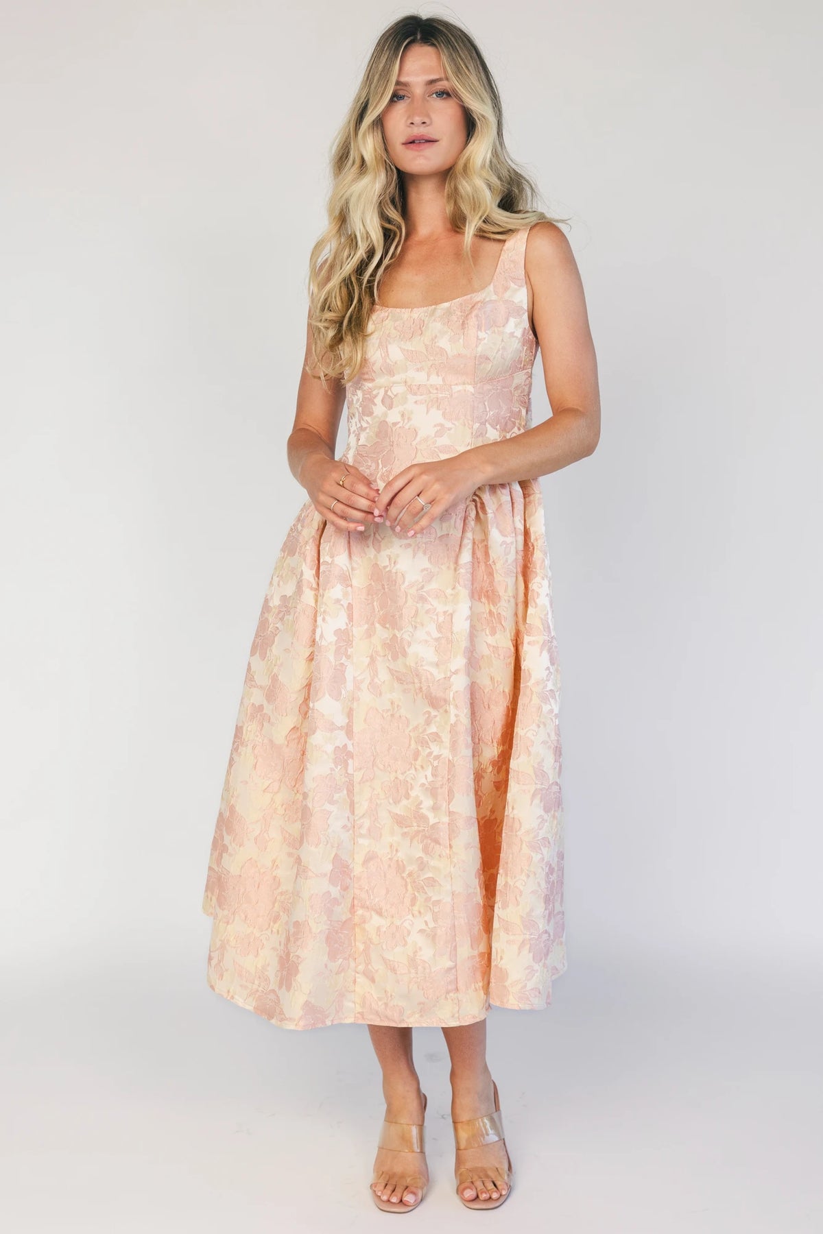 Model wearing a peach floral jacquard midi dress with a square neckline, wide tank straps, and a fitted bodice.