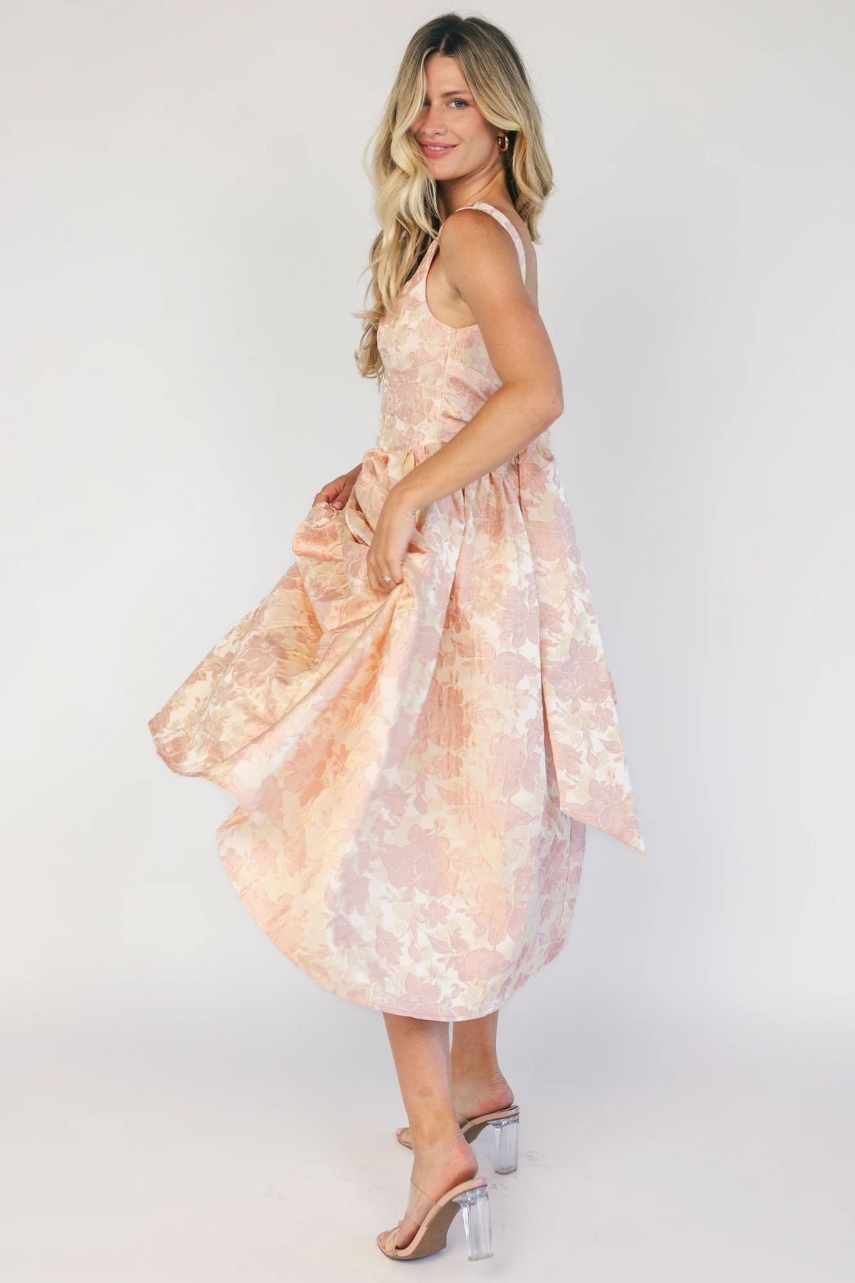 Model wearing a peach floral jacquard midi dress with a square neckline, wide tank straps, and a fitted bodice.