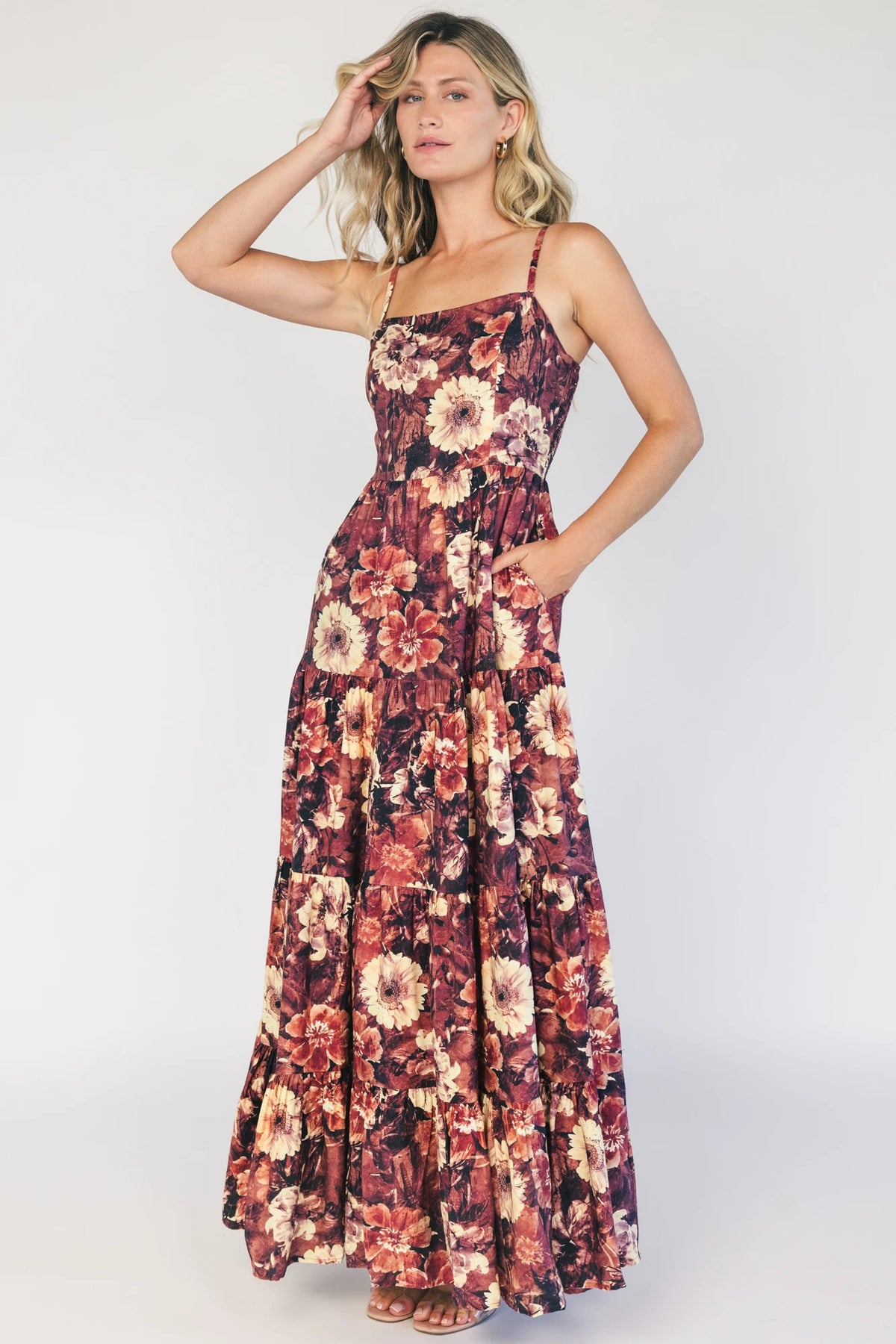 Model wearing a deep berry floral maxi dress with a square neckline, adjustable spaghetti straps, and a smocked back bodice.