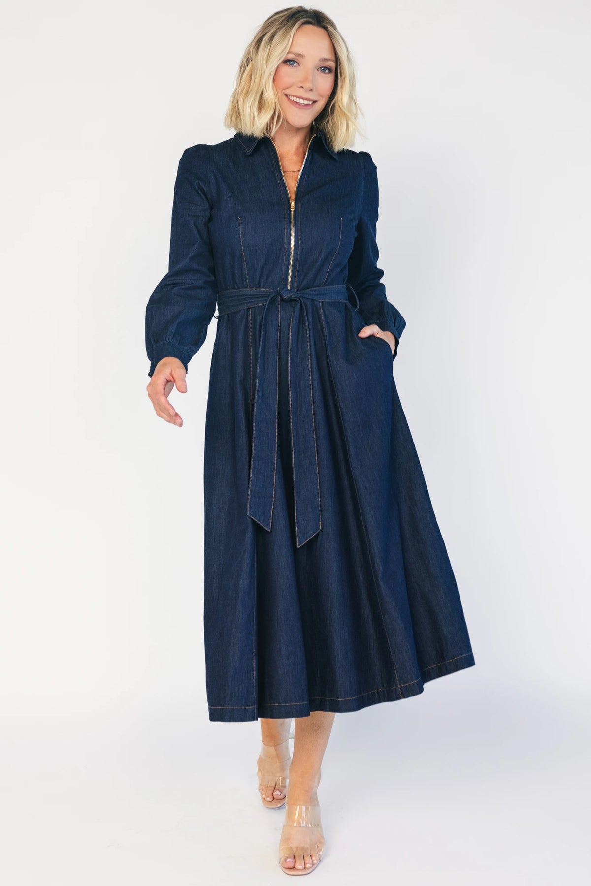 Model wearing a dark chambray midi shirtdress with a collared neckline, half-zip front, long sleeves, and a removable waist sash.