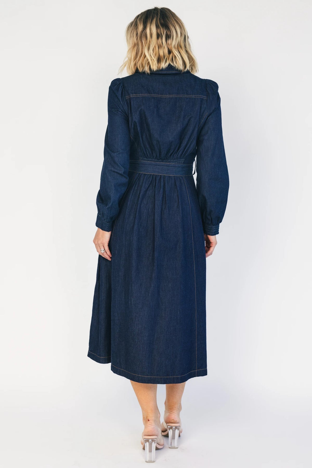 Model wearing a dark chambray midi shirtdress with a collared neckline, half-zip front, long sleeves, and a removable waist sash.