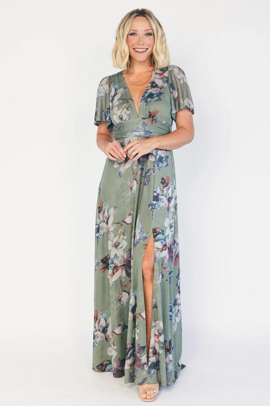 Model wearing a sage floral maxi dress with a deep V-neckline, short flutter sleeves, and an empire waist.