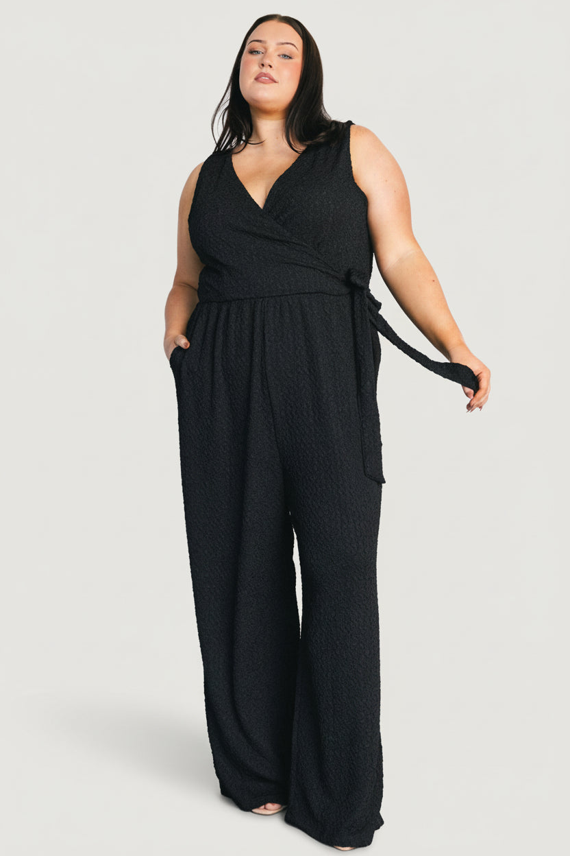 Three-quarter angle of the Natasha Jumpsuit in black showing wide pant leg drape and overall tailored silhouette.