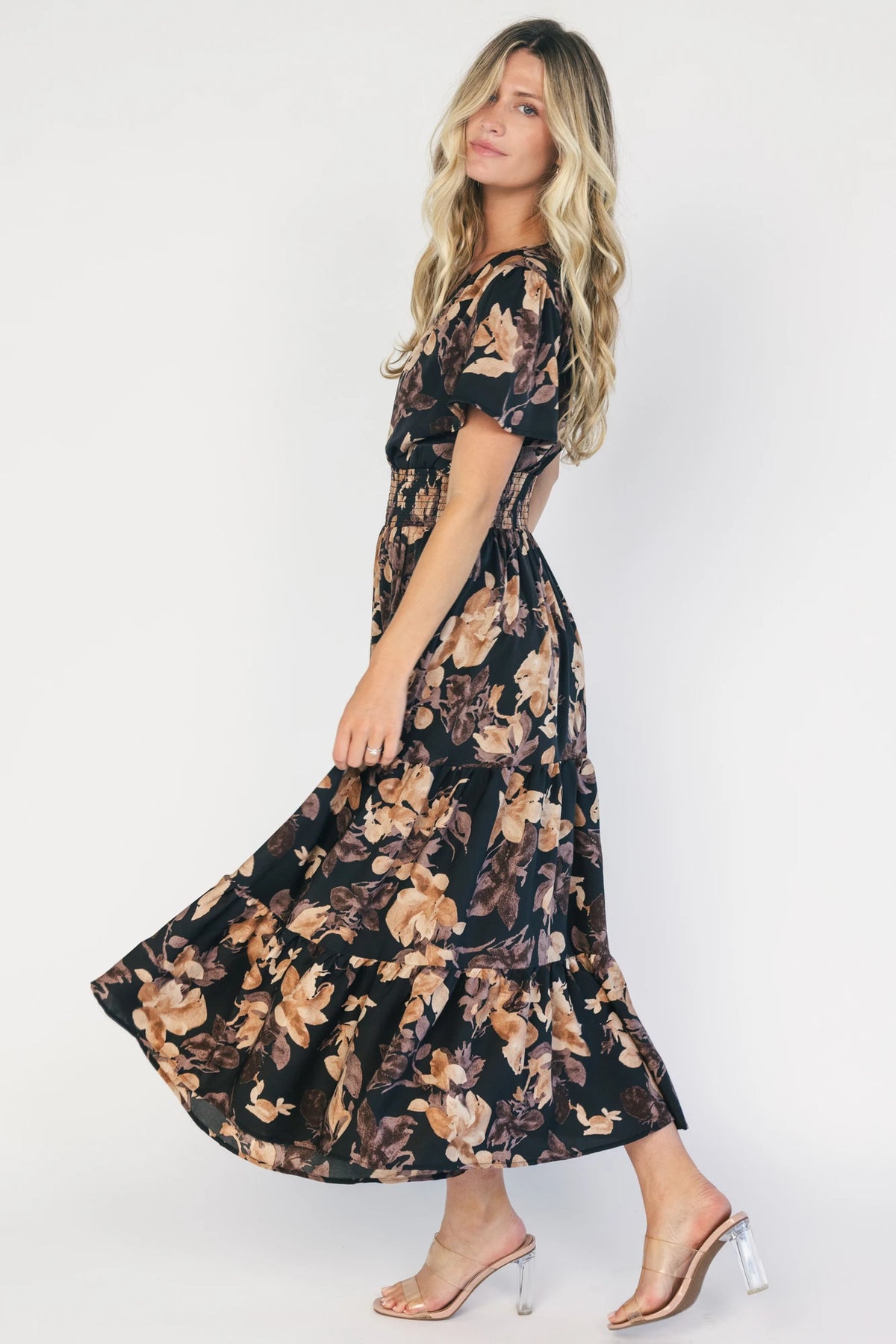 Model wearing a black floral midi dress with a V-neckline, short flutter sleeves, and a smocked waistband.