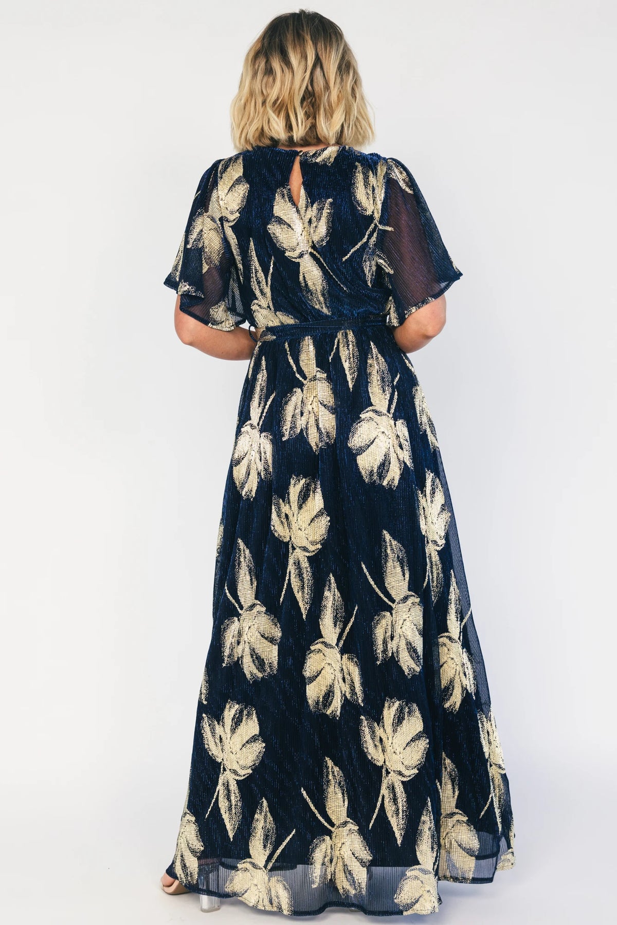 Rachel Maxi Dress in Navy + Gold with shimmer finish, surplice neckline, self-tie sash, long sleeves, and leg slit.