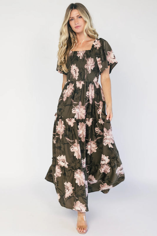 Dark olive floral maxi dress with a smocked bodice, square neckline, flutter sleeves, and a tiered ruffle skirt.