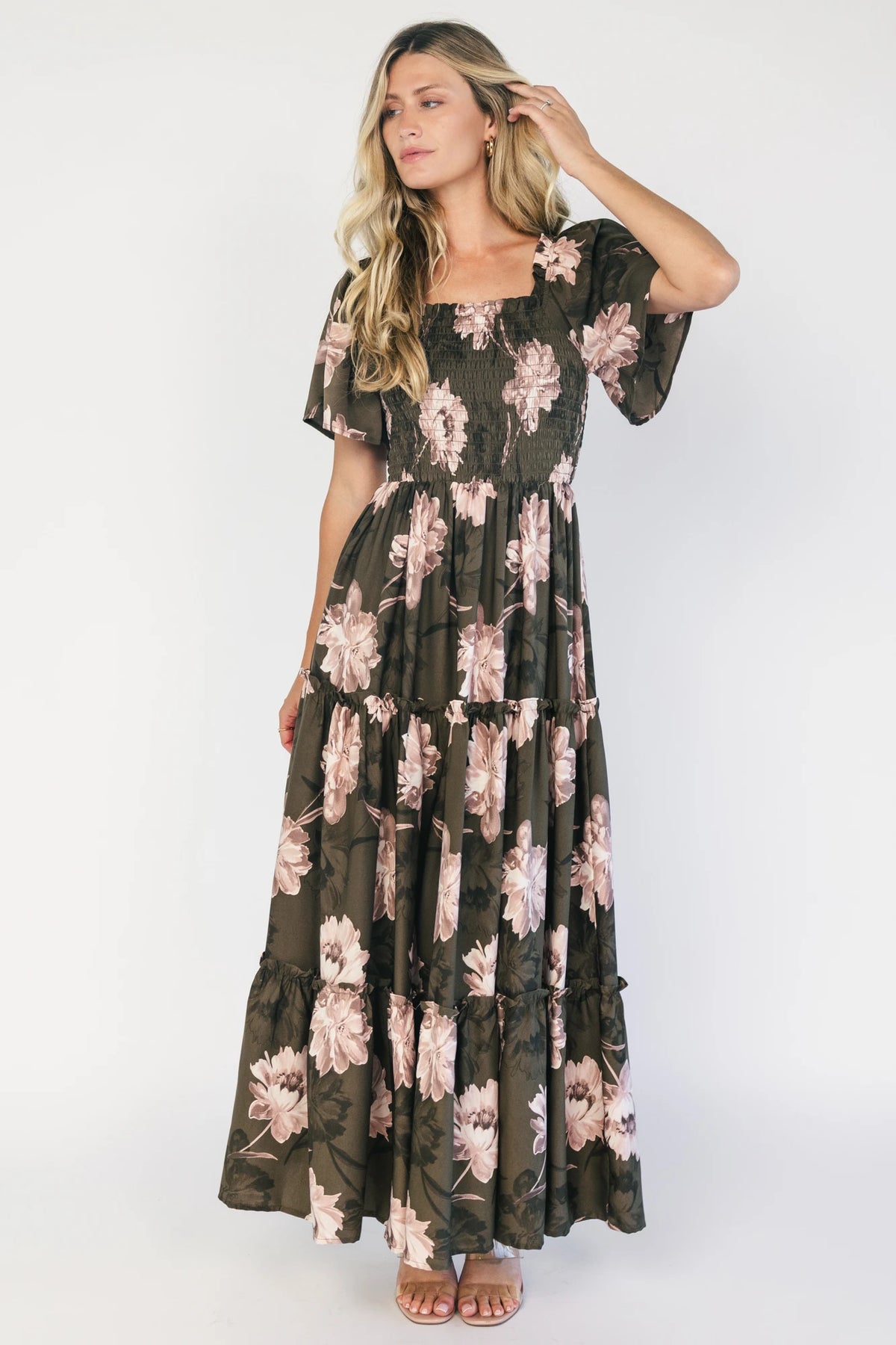 Dark olive floral maxi dress with a smocked bodice, square neckline, flutter sleeves, and a tiered ruffle skirt.