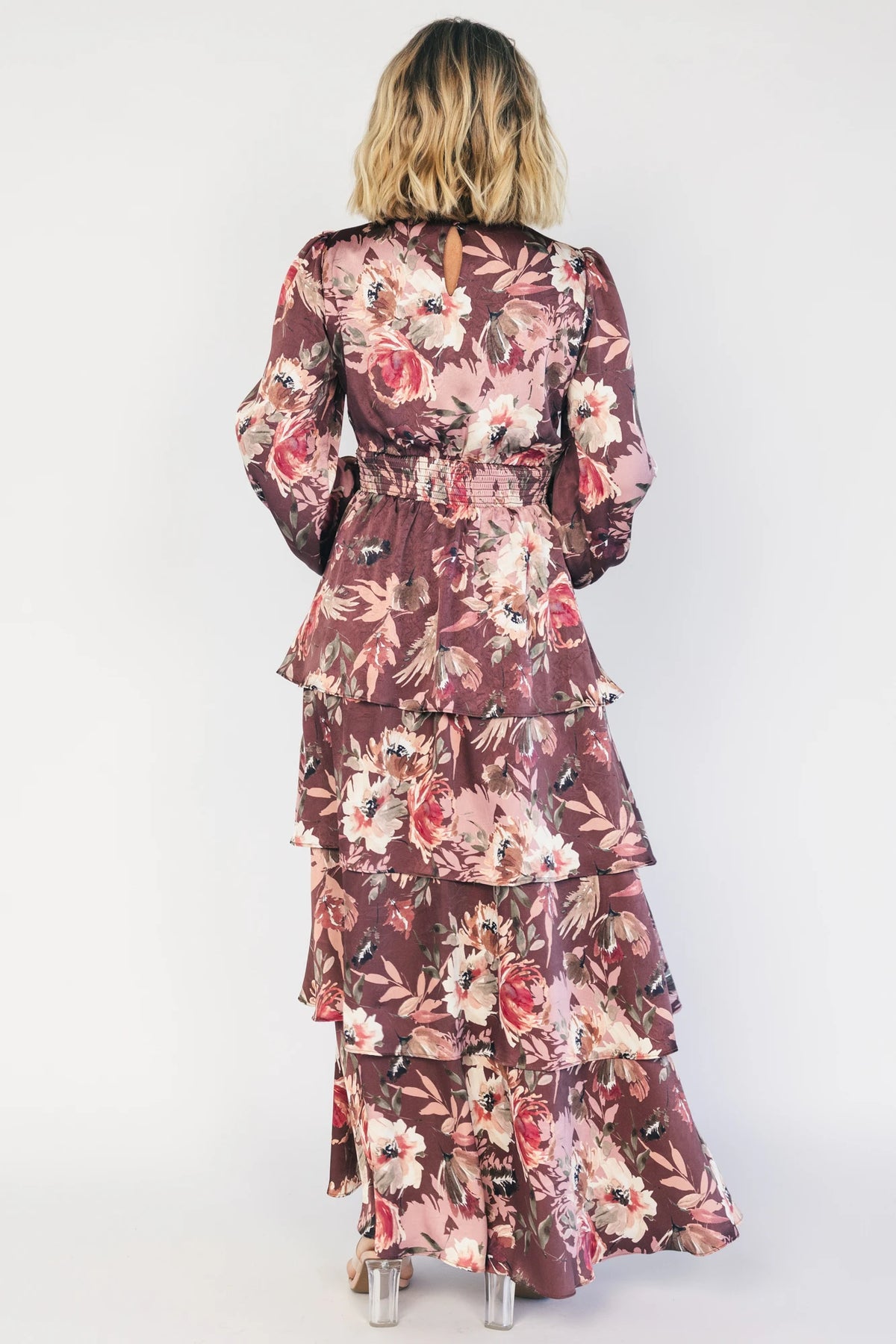 Clove satin maxi dress with a mauve floral print, V-neckline, short sleeves, a smocked back, and a flowing tiered ruffle skirt.