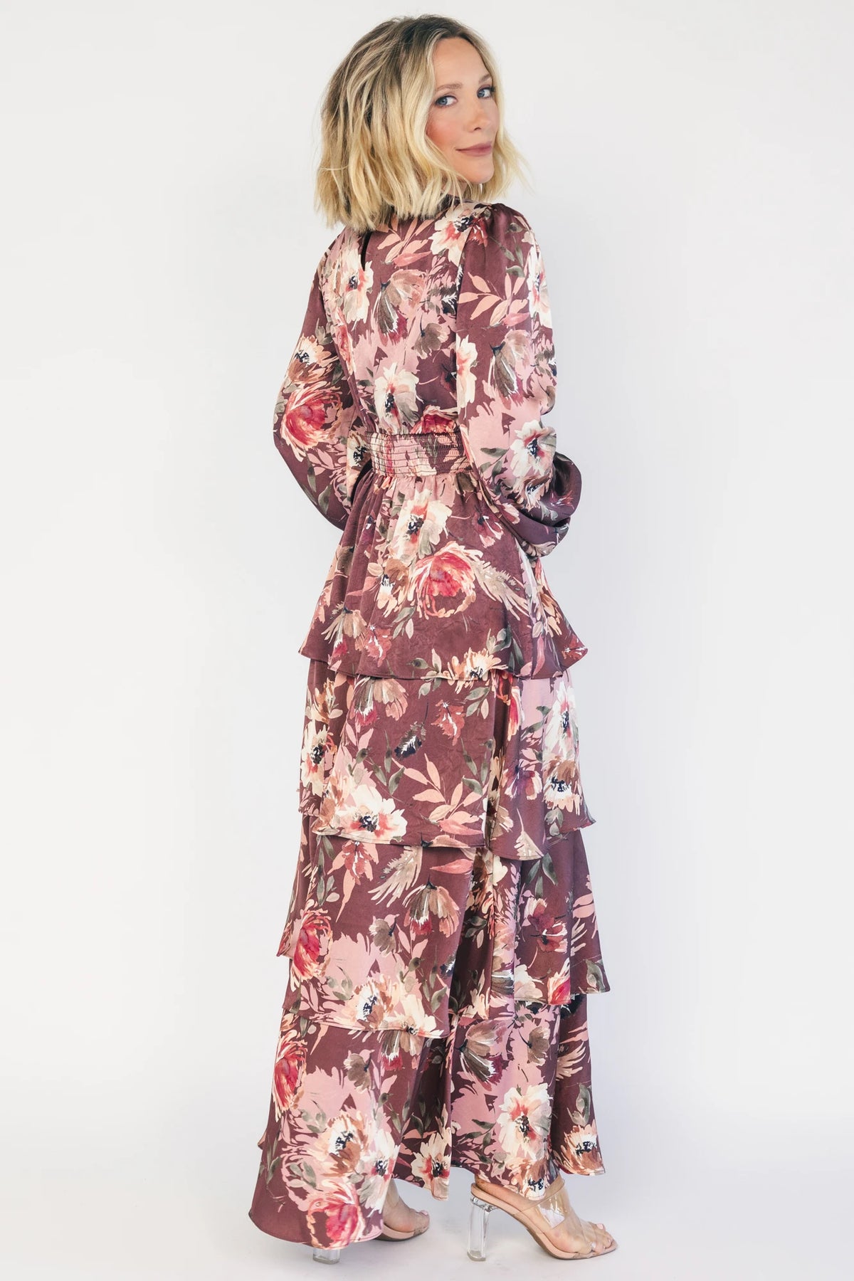 Clove satin maxi dress with a mauve floral print, V-neckline, short sleeves, a smocked back, and a flowing tiered ruffle skirt.