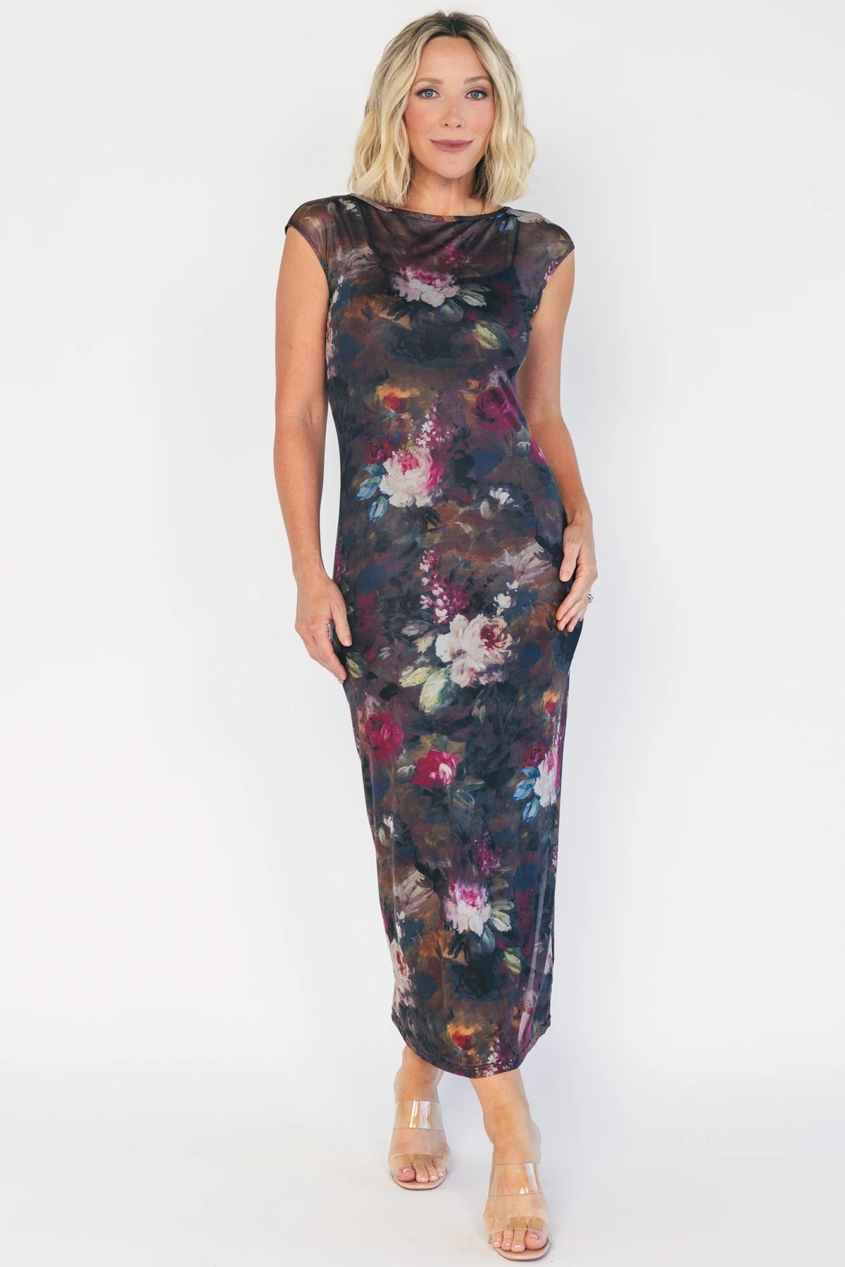 Model wearing the Daniela Mesh Midi Dress in Brown Floral, a fitted mesh midi dress with a brown floral print, round neckline, short sleeves, and a bodycon silhouette layered over a ribbed slip.