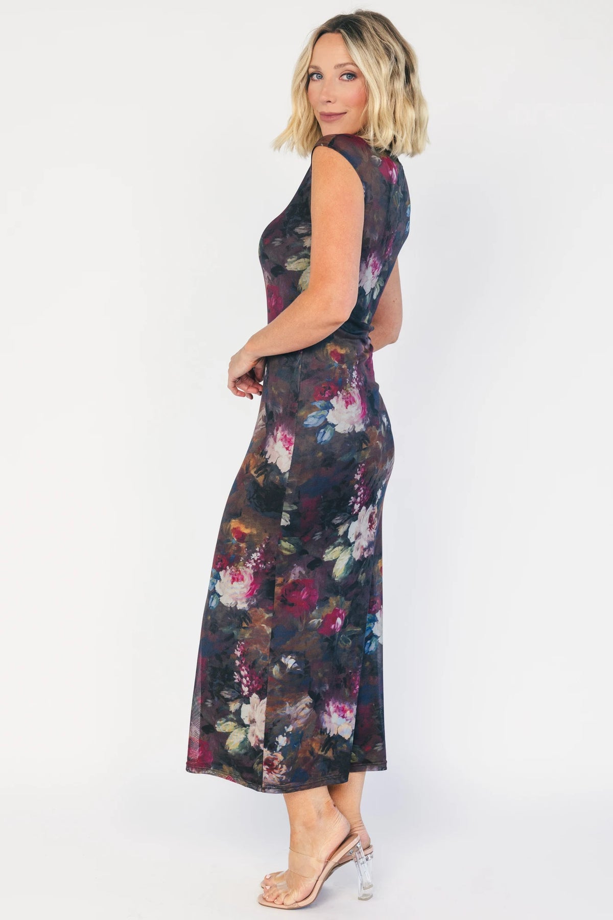 Model wearing the Daniela Mesh Midi Dress in Brown Floral, a fitted mesh midi dress with a brown floral print, round neckline, short sleeves, and a bodycon silhouette layered over a ribbed slip.