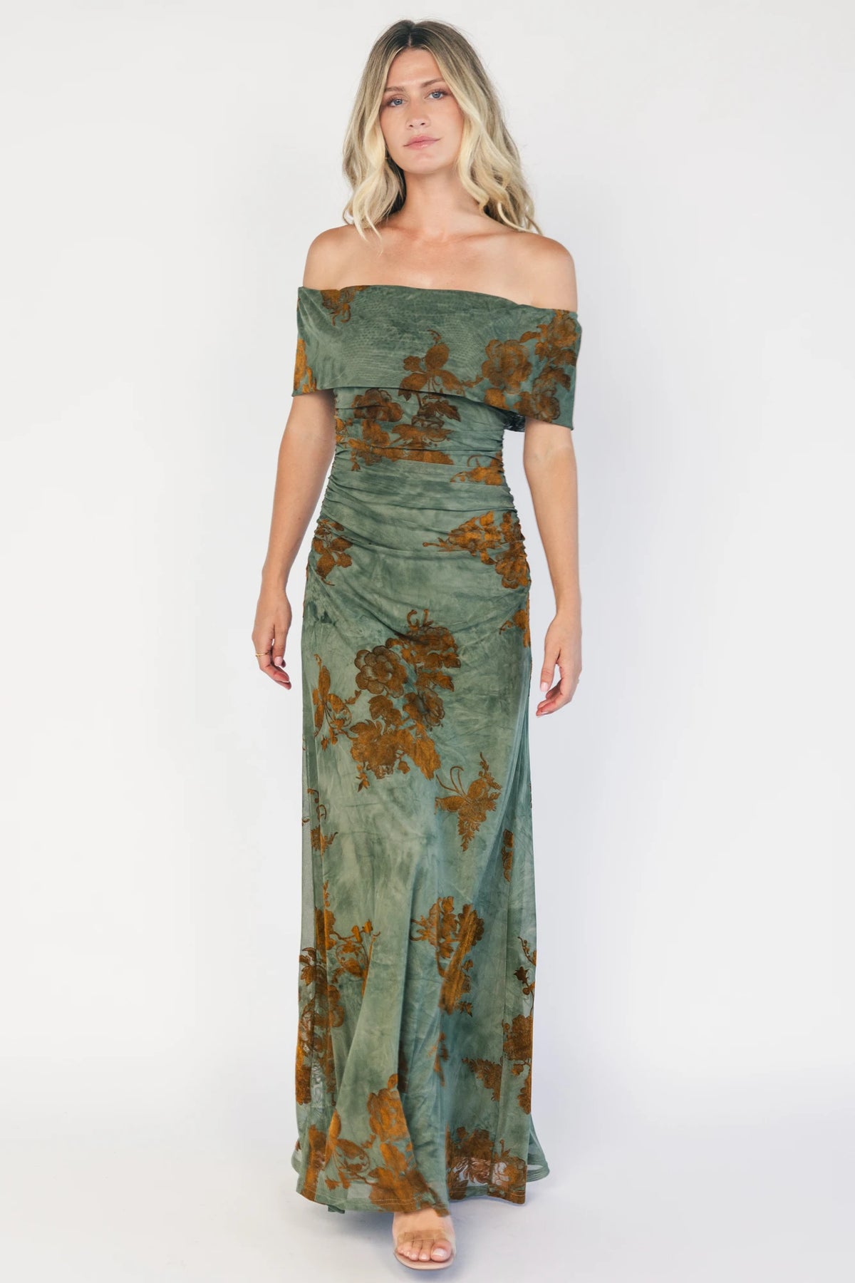Model wearing an off-the-shoulder maxi dress with a green mesh overlay and copper velvet floral detailing.