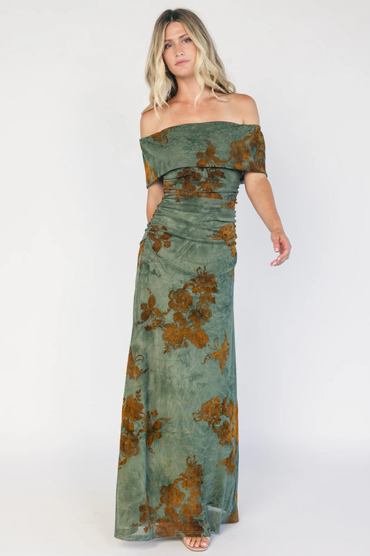 Model wearing an off-the-shoulder maxi dress with a green mesh overlay and copper velvet floral detailing.