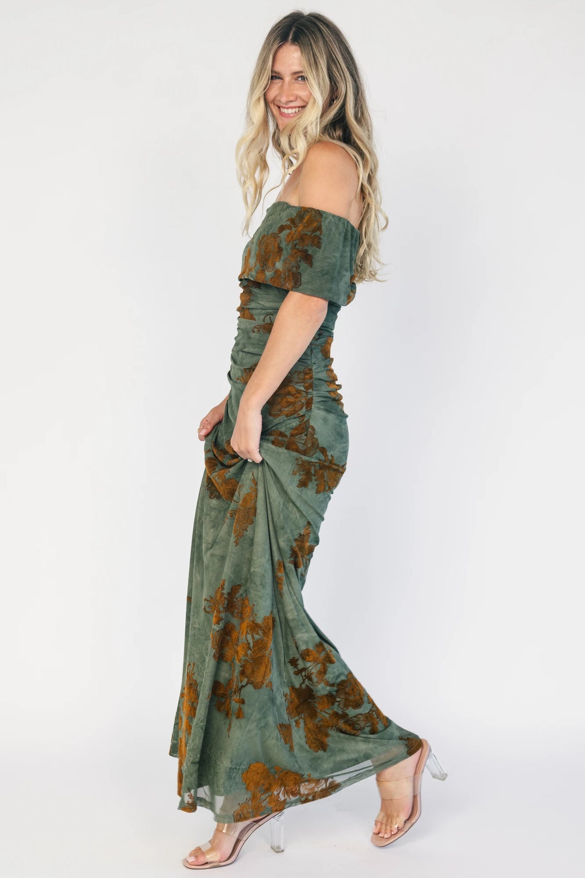 Model wearing an off-the-shoulder maxi dress with a green mesh overlay and copper velvet floral detailing.
