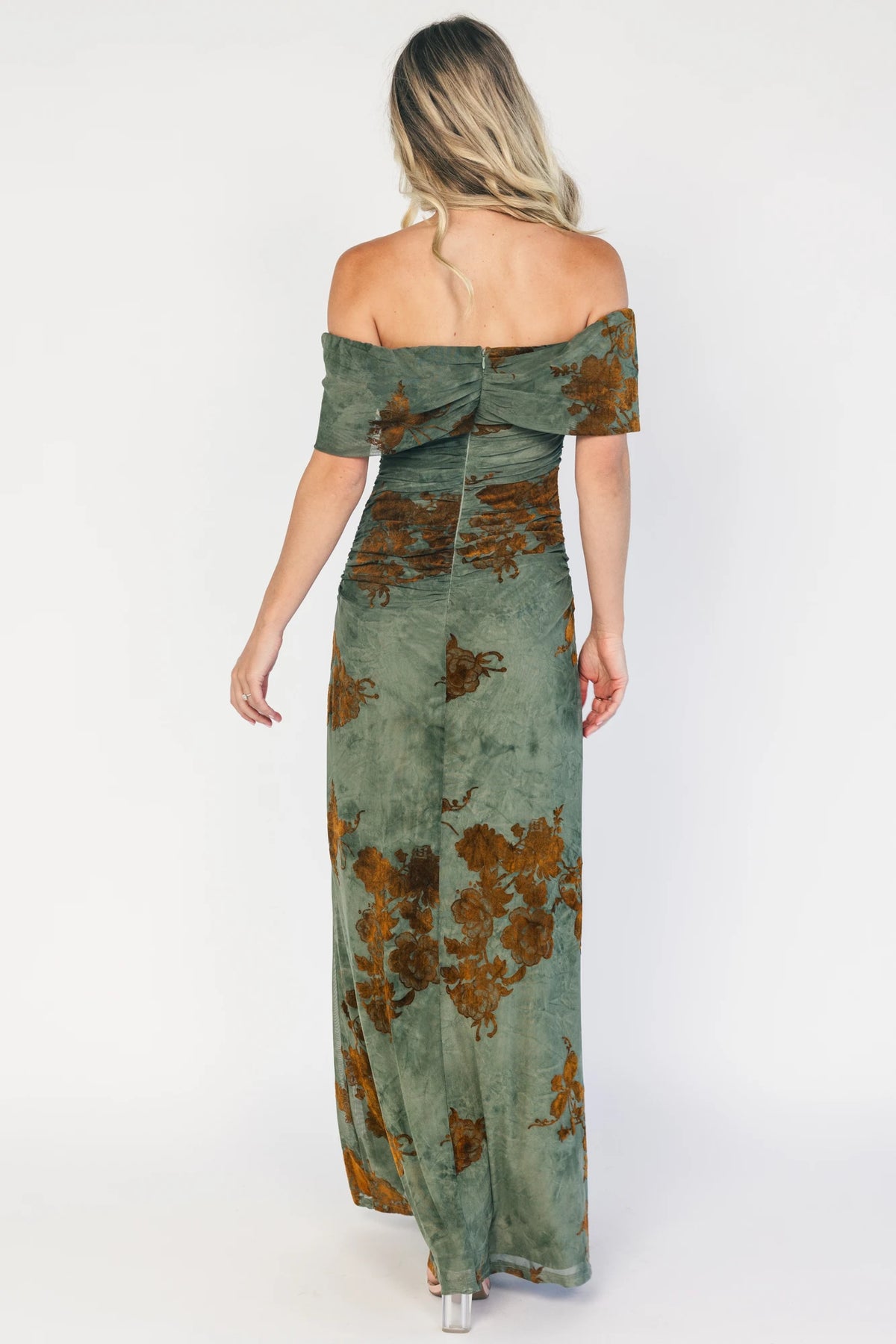 Model wearing an off-the-shoulder maxi dress with a green mesh overlay and copper velvet floral detailing.