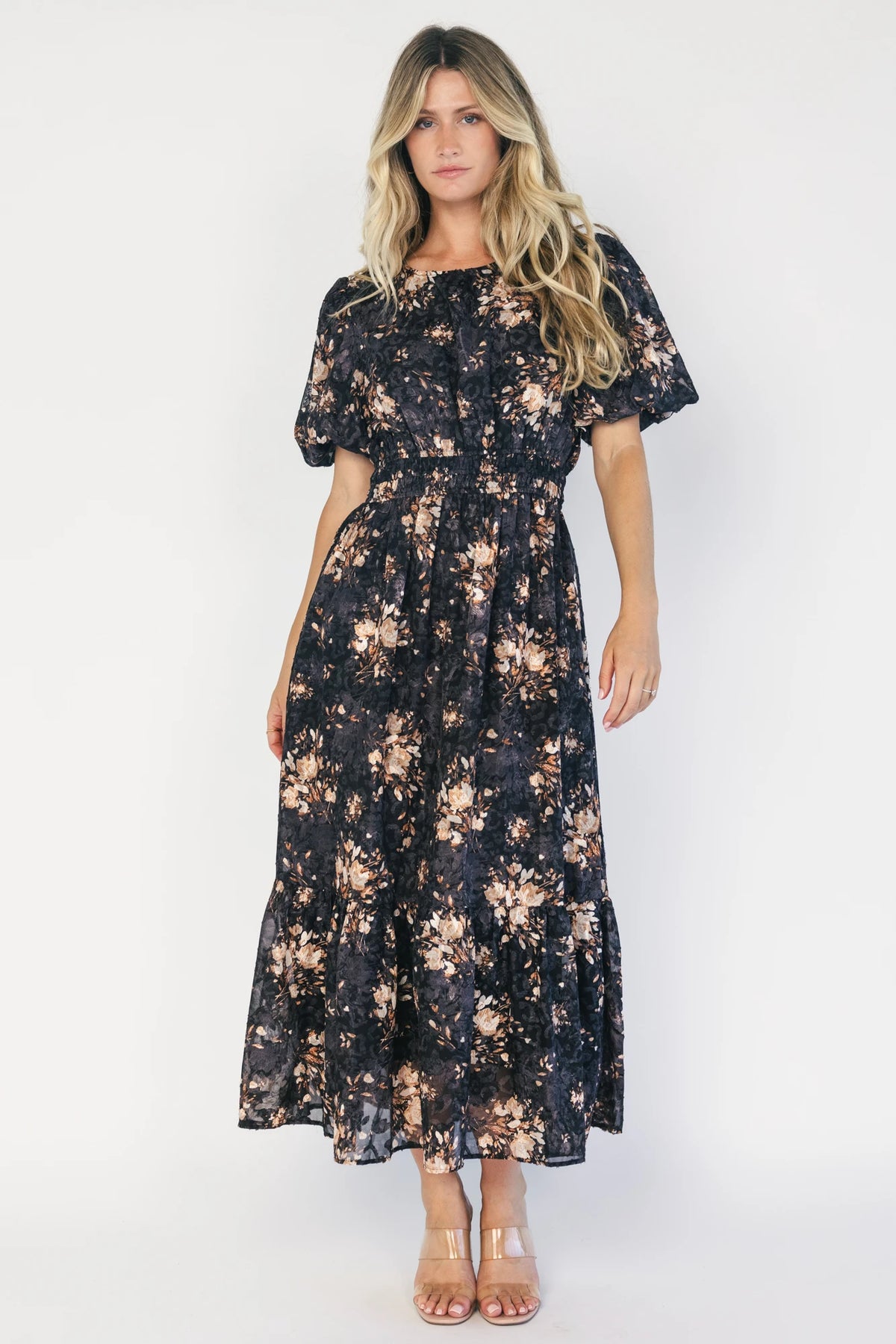 Model wearing a black floral midi dress with a round neckline, puff sleeves, and a smocked waist.