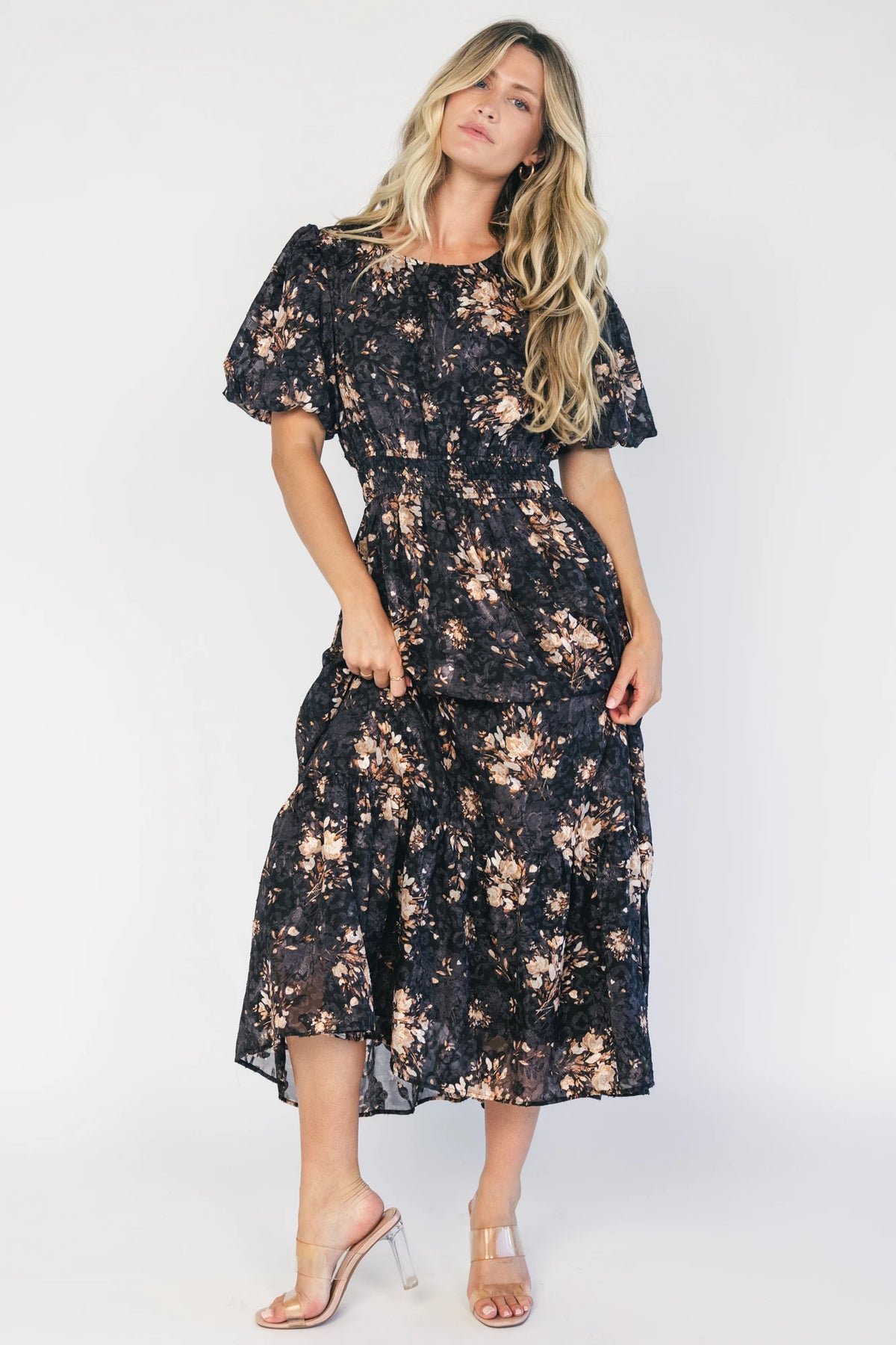 Model wearing a black floral midi dress with a round neckline, puff sleeves, and a smocked waist.