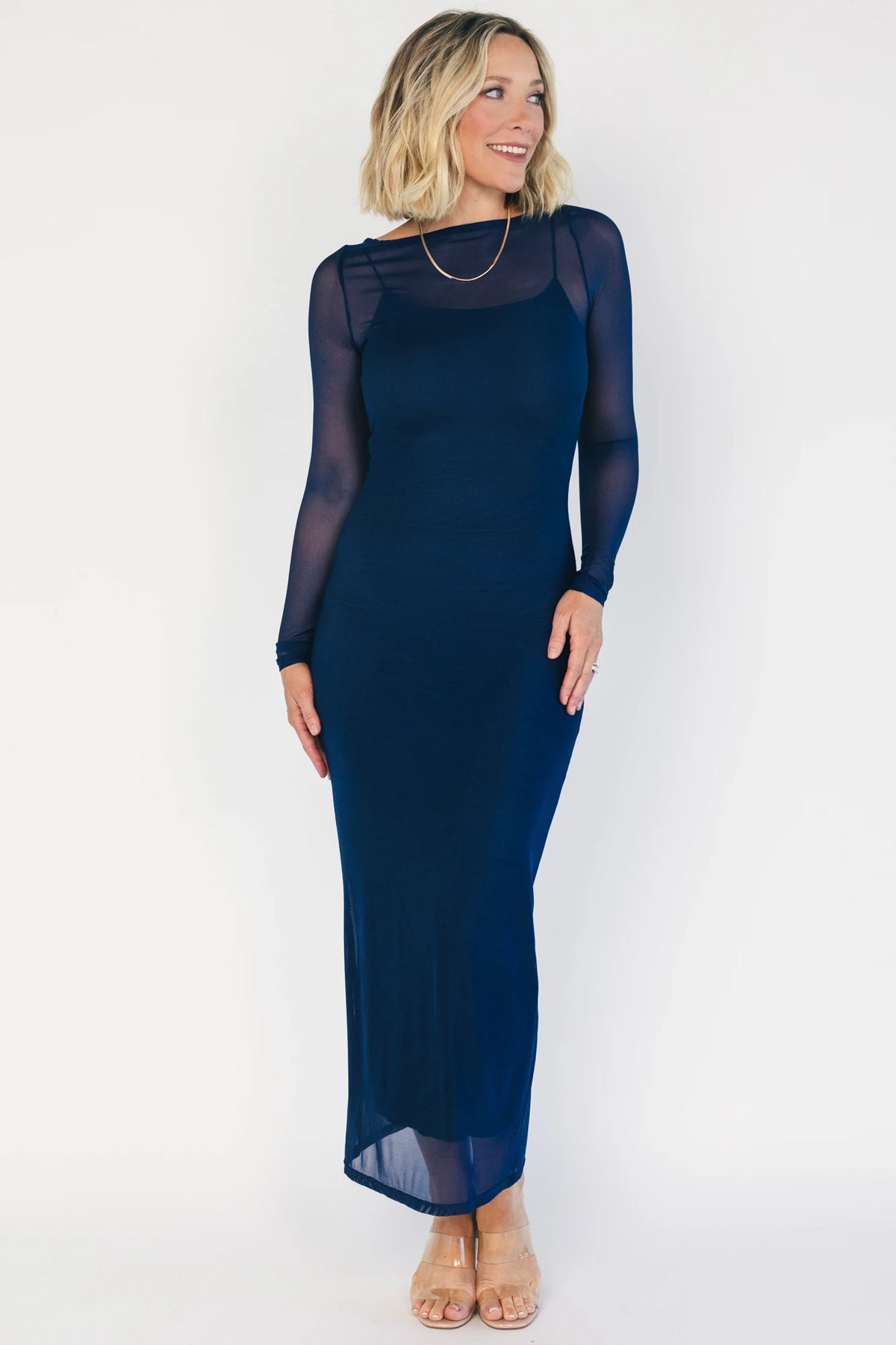 Model wearing the Darya Mesh Midi Dress in Navy featuring a sheer mesh overlay with a round neckline, long sleeves, and a fitted bodycon midi silhouette layered over a matching ribbed slip.