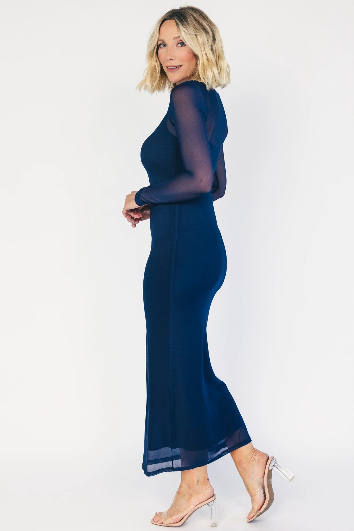 Model wearing the Darya Mesh Midi Dress in Navy featuring a sheer mesh overlay with a round neckline, long sleeves, and a fitted bodycon midi silhouette layered over a matching ribbed slip.