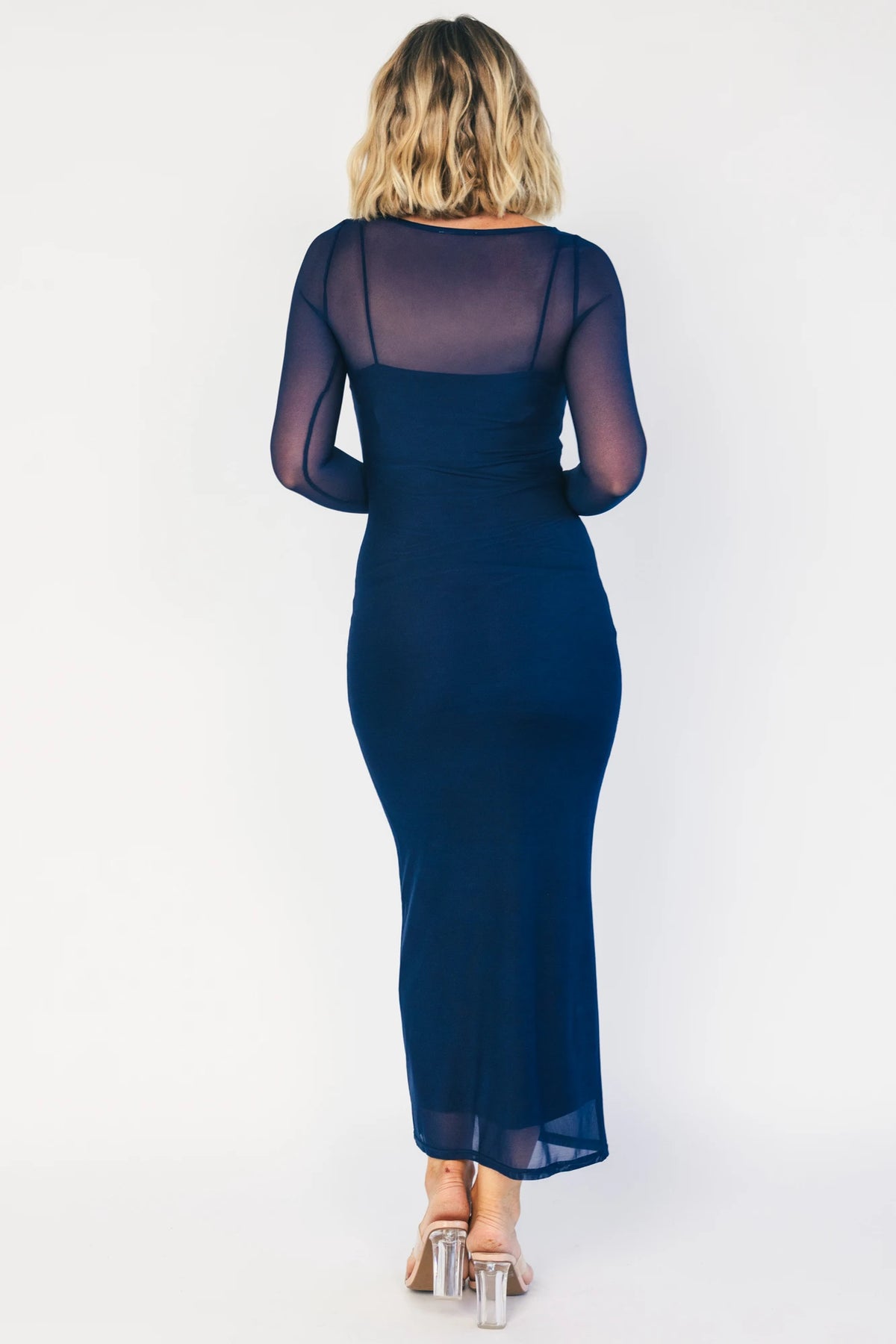 Model wearing the Darya Mesh Midi Dress in Navy featuring a sheer mesh overlay with a round neckline, long sleeves, and a fitted bodycon midi silhouette layered over a matching ribbed slip.