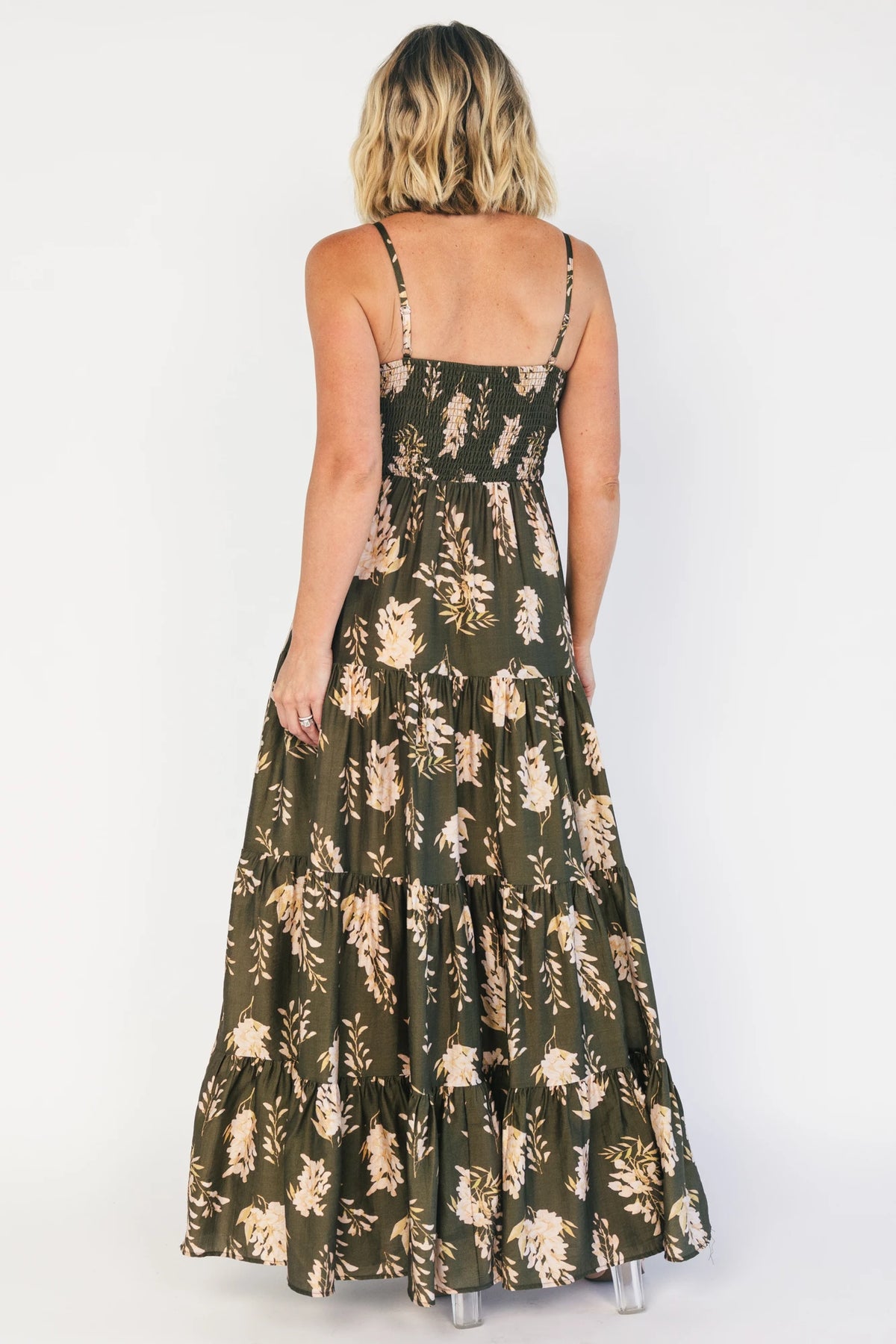Model wearing an olive floral maxi dress with a square neckline, adjustable spaghetti straps, and a smocked back bodice.