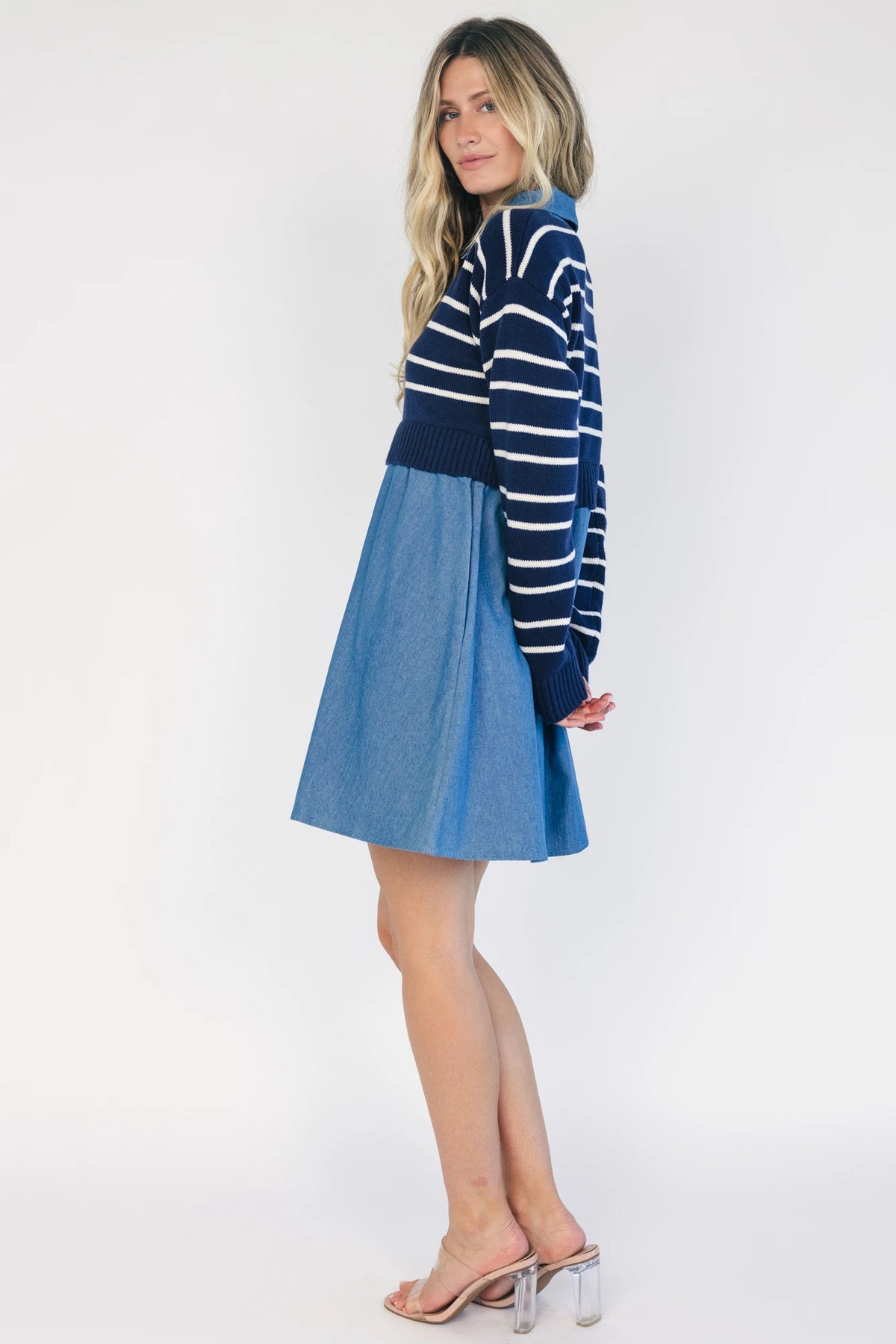 Model wearing a navy and ivory striped sweater dress with a collared neckline, functional button-front detail, long sleeves, and an elastic waist.