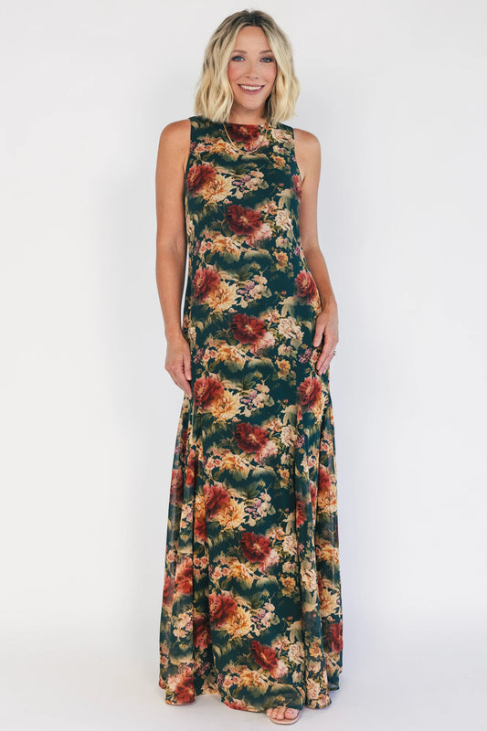 Model wearing a topaz floral maxi dress with a high round neckline, sleeveless bodice, and an open back with a sash tie.