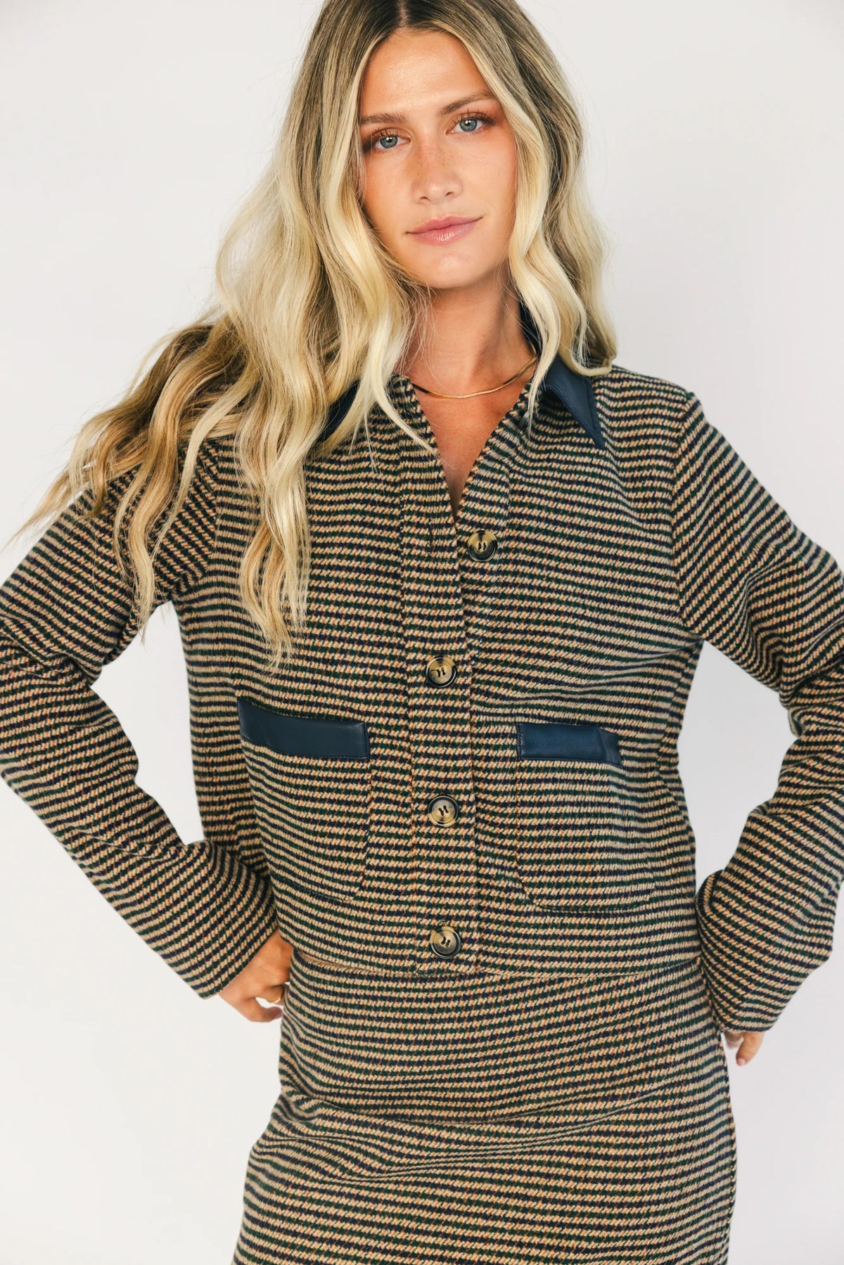Model wearing the Gracey Set in Navy + Tan featuring a navy and tan striped tweed jacket with a collared neckline, faux leather trim, button-front closure, and matching mini skirt for a polished, coordinated look.