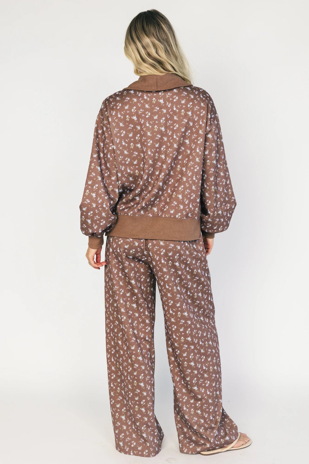 Model wearing the Diana Lounge Set in Brown Floral featuring a matching long-sleeve half-zip top and wide-leg pants.